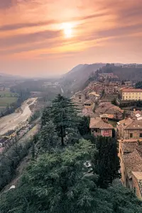 Il tramonto sulla Val d’Arda visto da Castell’Arquato, con i tetti del borgo e il greto del torrente Arda